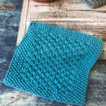Blue textured knit dishcloth on box with yarn bowl.