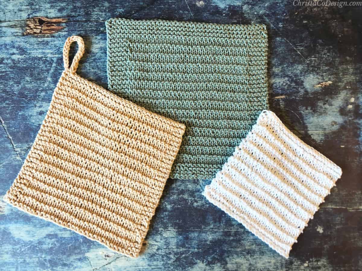 Beige, green and white knit dishcloths on blue background.