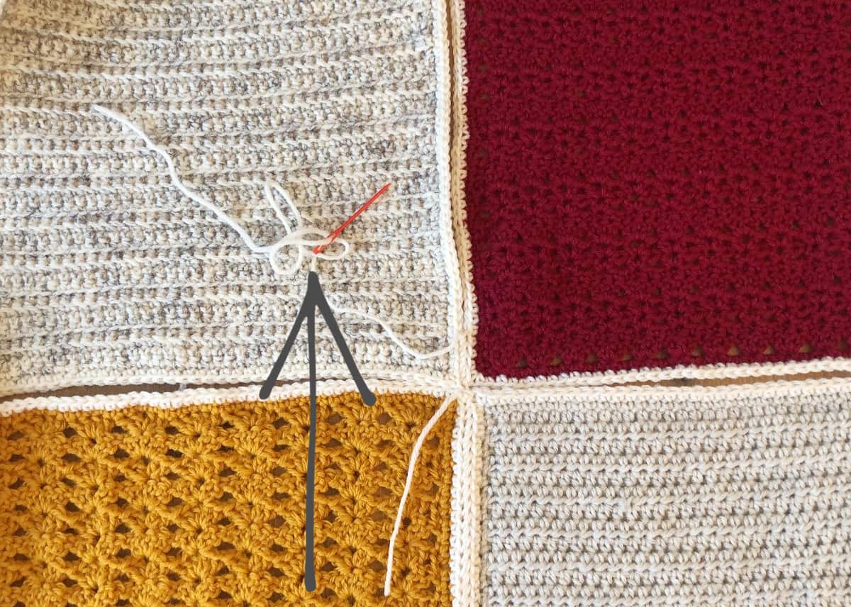 4 blanket squares in red, gold and white being sewn together with arrow showing direction of work.