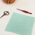 Square dishcloth with hook, scissors, and yarn in copper yarn bowl.