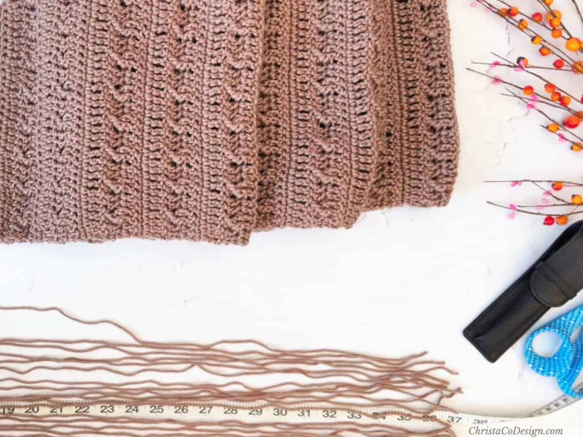 Lengths of yarn laid out next to scarf and measuring tape.