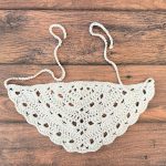 Crochet bandana with ties on wood table.
