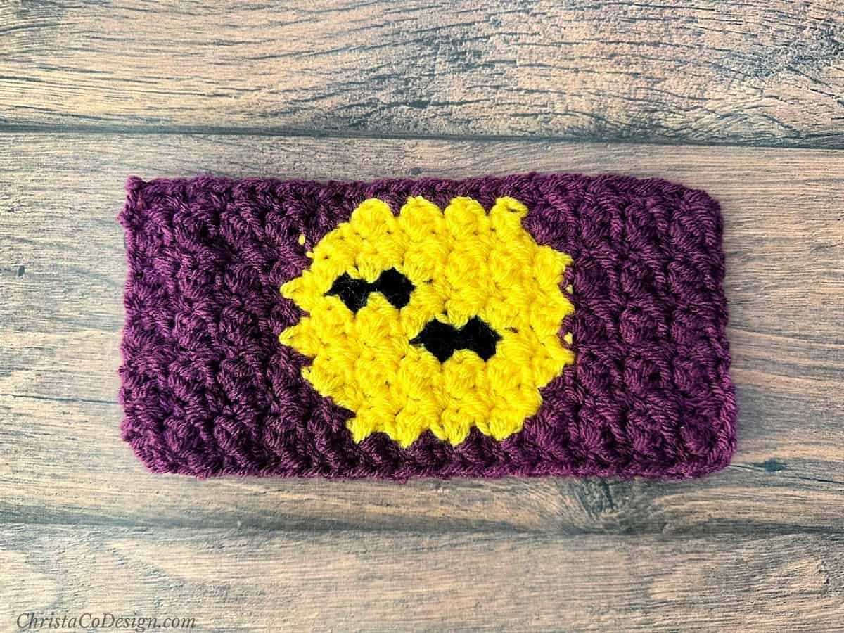 Crochet cup cozy laid flat with bats over moon.
