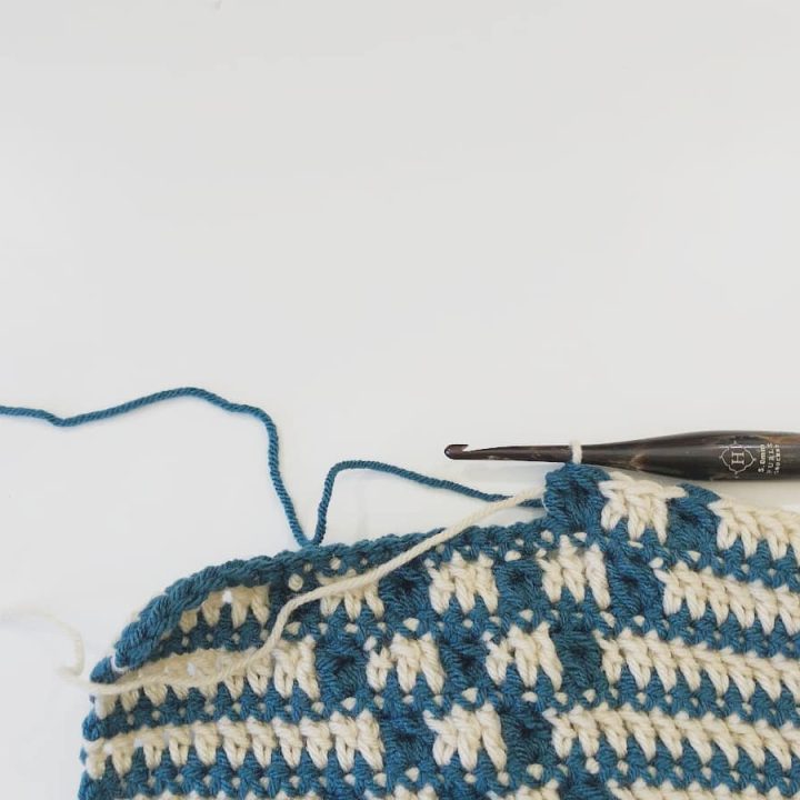 Crochet blanket square in blue bobble stitch and beige double crochet.