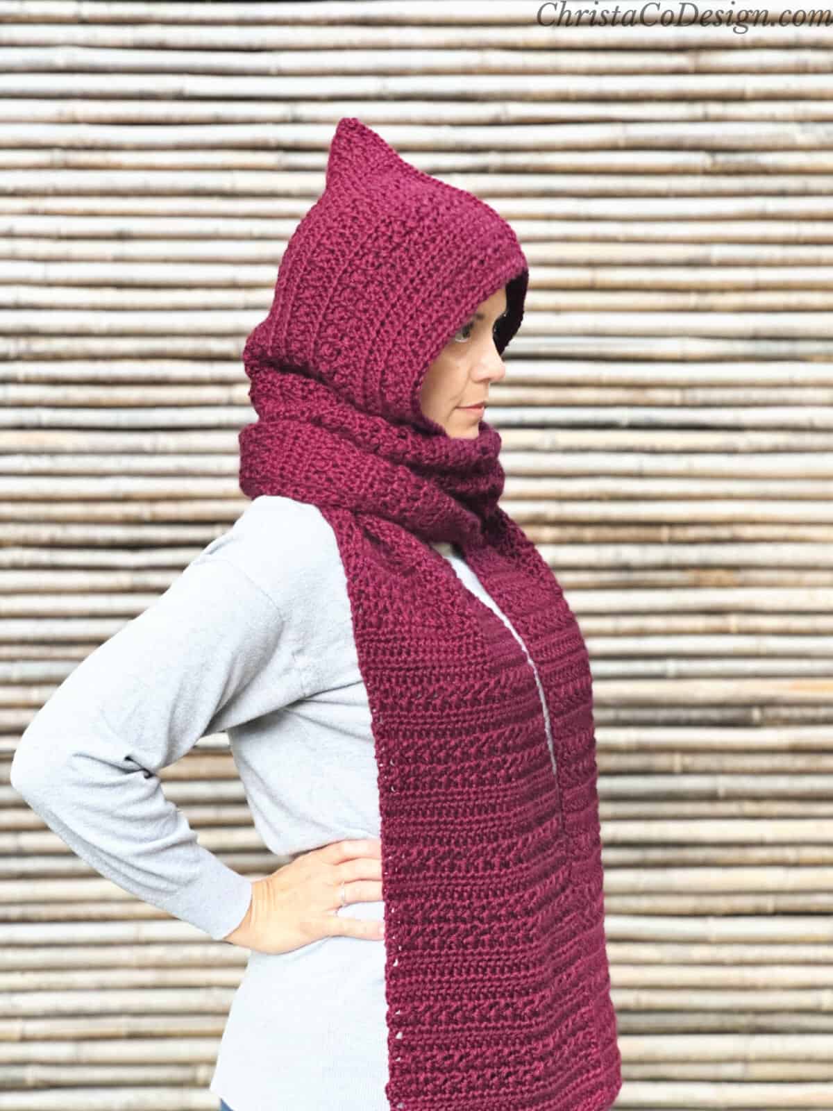 Woman with maroon crochet hooded scarf on turned to the side.