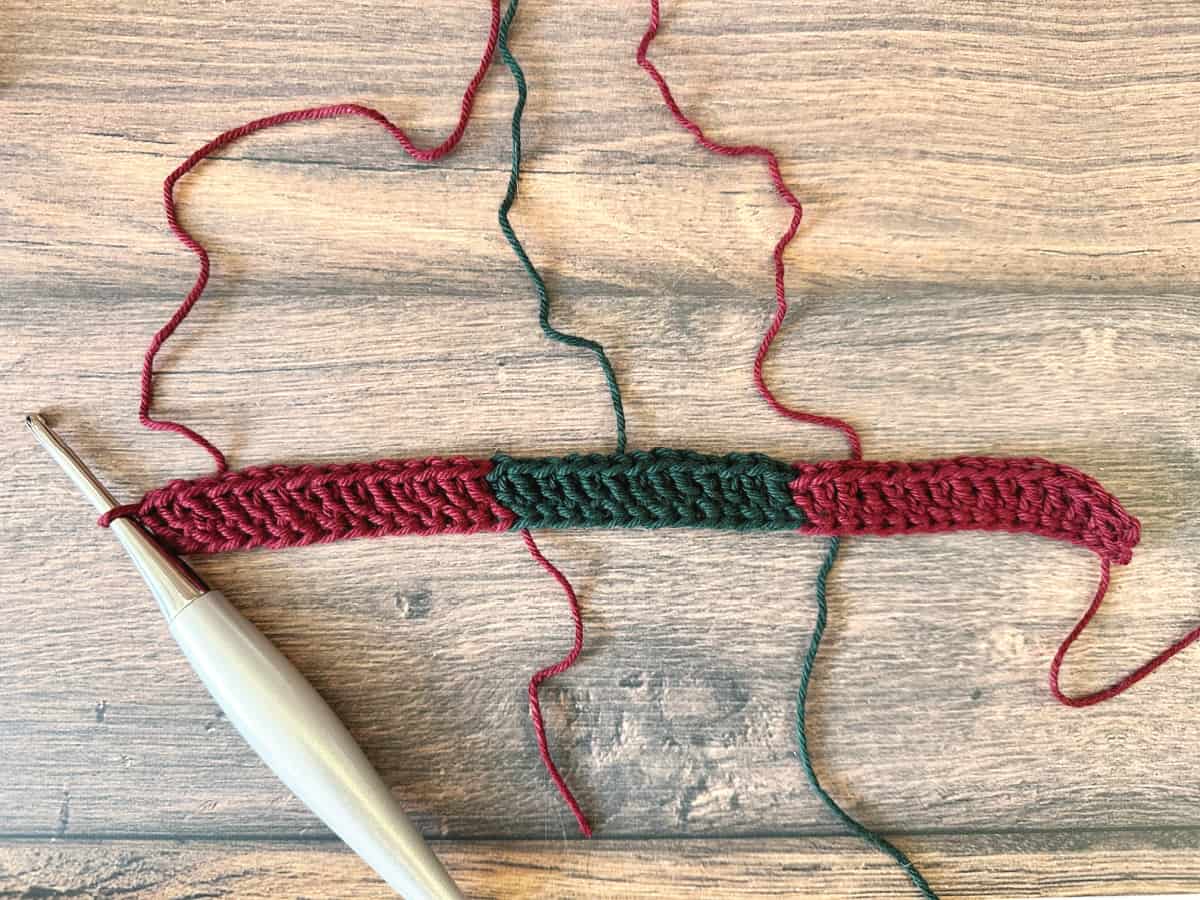 Crochet hook with foundation double crochet row in reds and green.