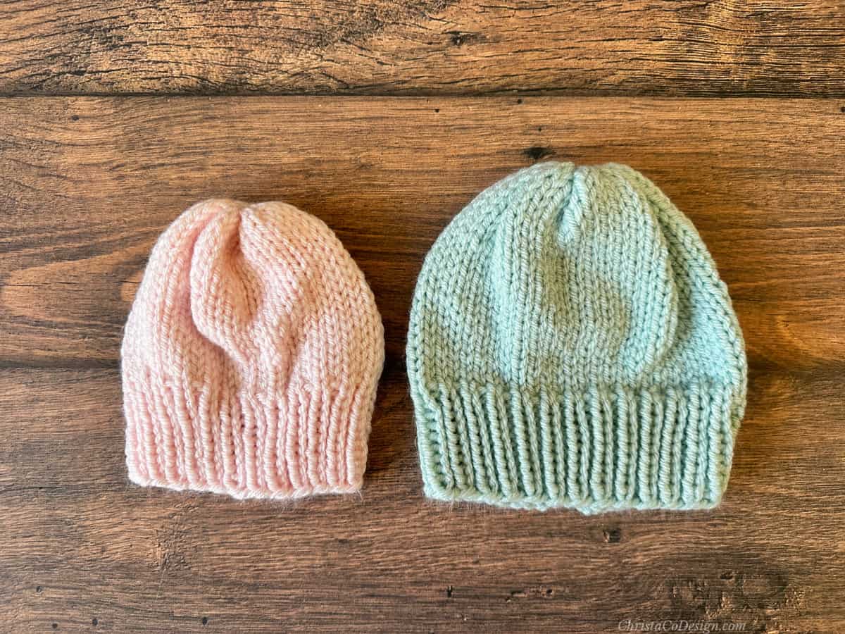 Pink and blue knit baby hats side by side.