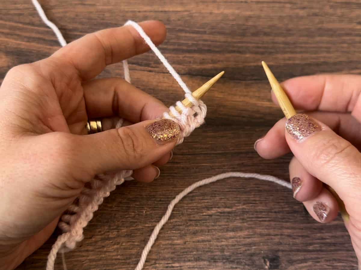 Needle with live stitches in right hand.