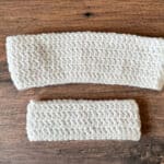 Two crochet headbands in white on wood table.