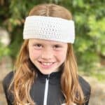 Girl wearing white crochet headband in black zip up.