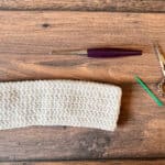 Double crochet headband pattern in white with hook and scissors, yarn needle.