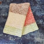 Striped knit dish towel folded over to show stripes in red, green, brown and cream.