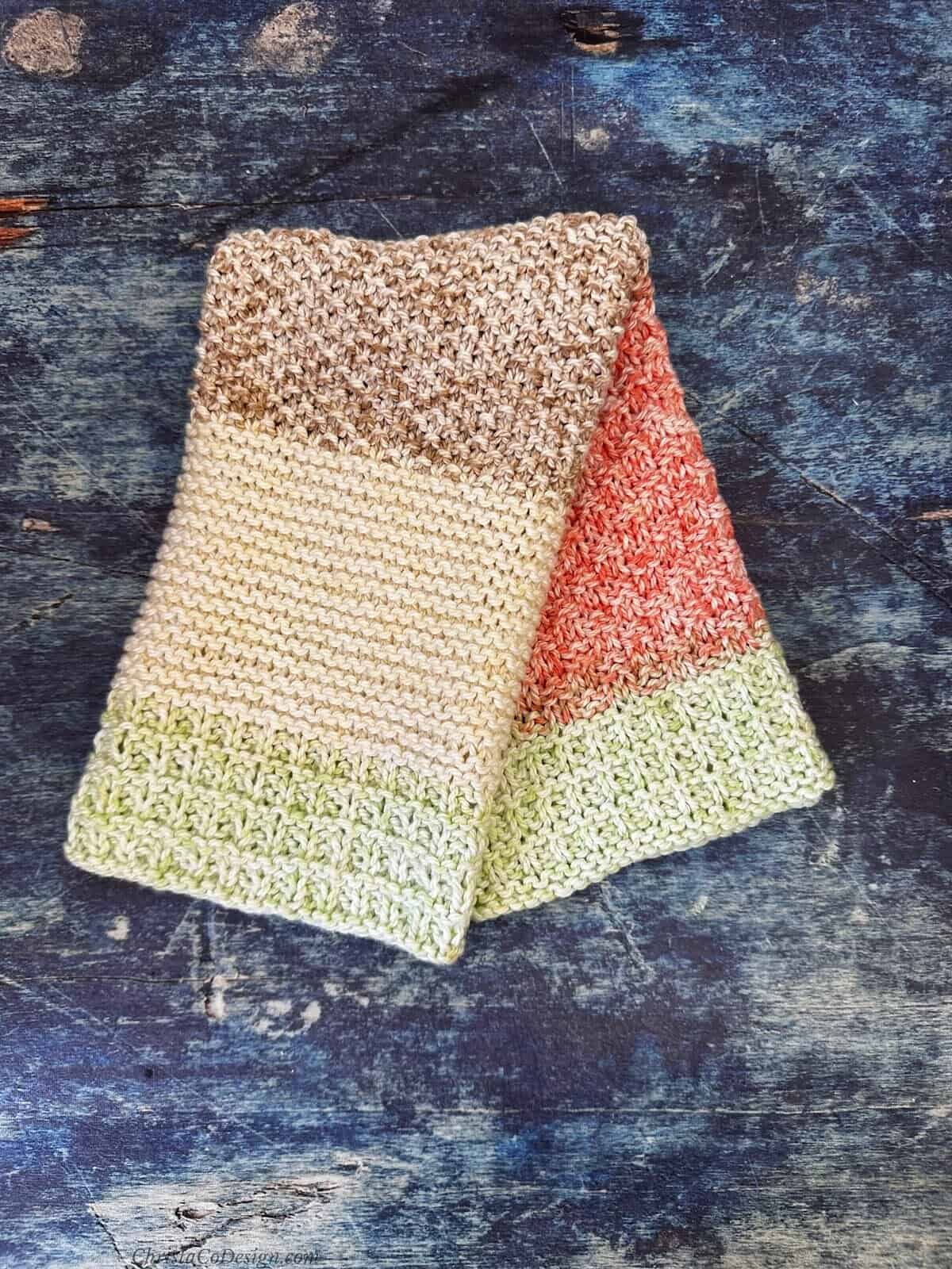 Striped knit dish towel folded over to show stripes in red, green, brown and cream.