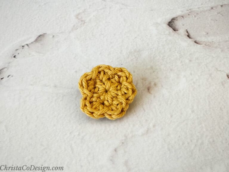 Small crochet flower in gold yarn.