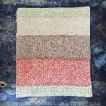 Colorful knit dish towel laid out flat too show stripes.