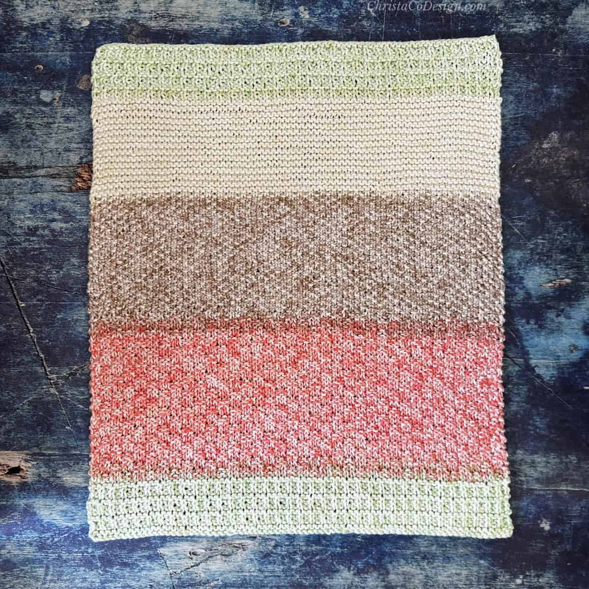 Colorful knit dish towel laid out flat too show stripes.