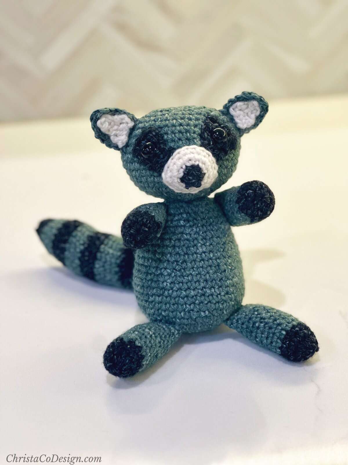 Crochet raccoon on white counter.