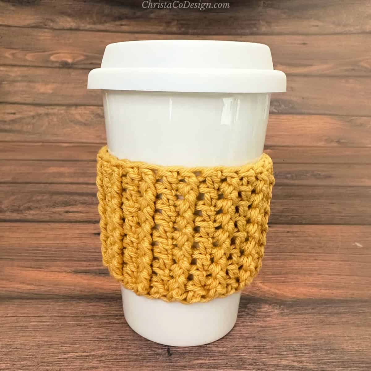 White coffee cup with ribbed yellow crochet cozy.