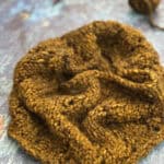 Chunky knit cowl with needles and yarn.