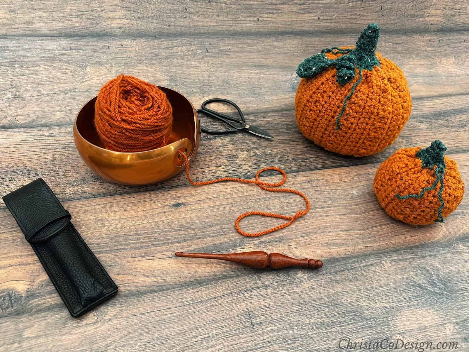 Two crochet pumpkins with notions and yarn.