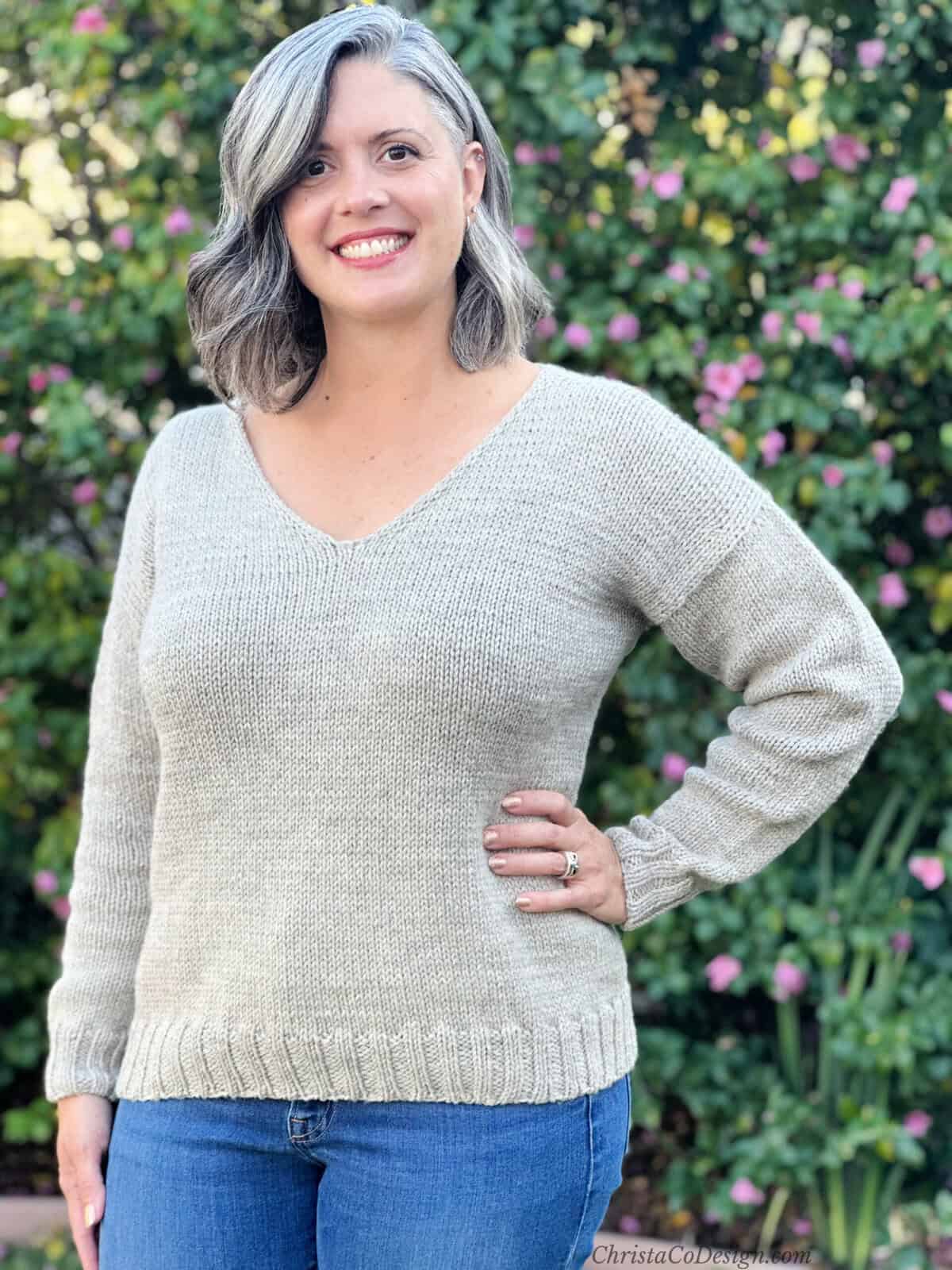 Woman smiling with knit sweater in beige yarn.