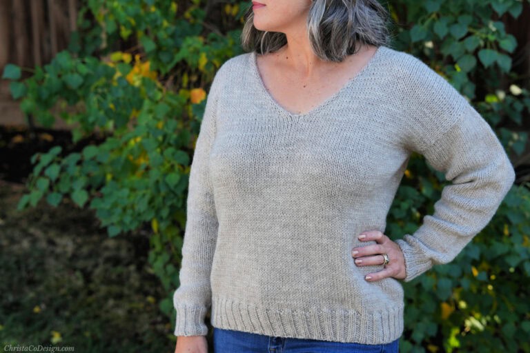 Women in beige knit v-neck sweater.