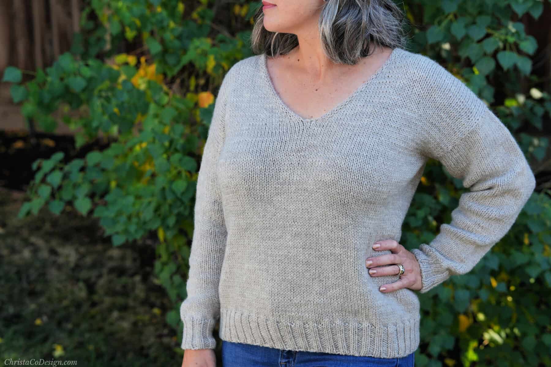 Women in beige knit v-neck sweater.