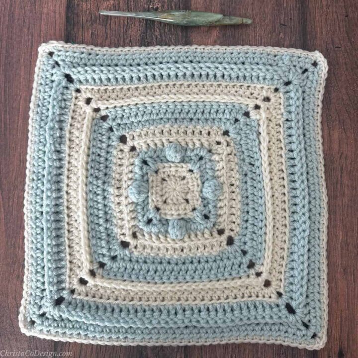 12 inch blue and white blanket square with crochet hook.