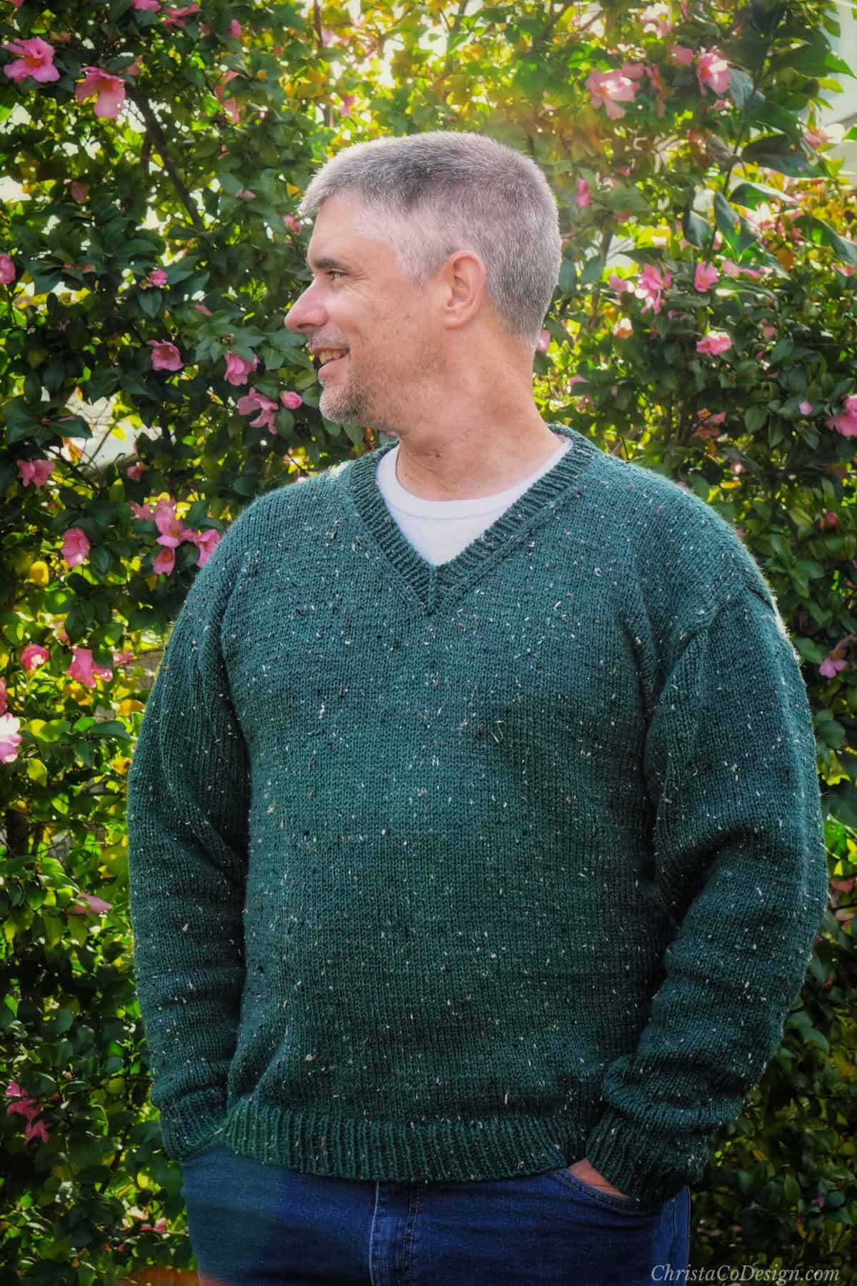 Man in green knit v-neck sweater with head turned.