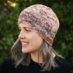 Woman in multi colored beanie with head turned to side.