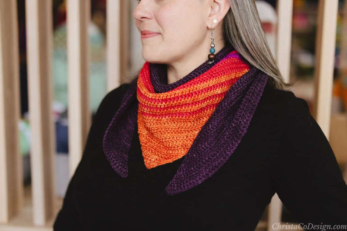 Woman in block top with crochet scarf in colors of sunset.