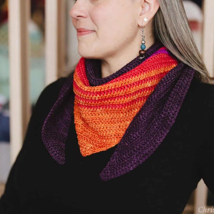 Woman in block top with crochet scarf in colors of sunset.