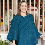 Smiling woman in crochet poncho.