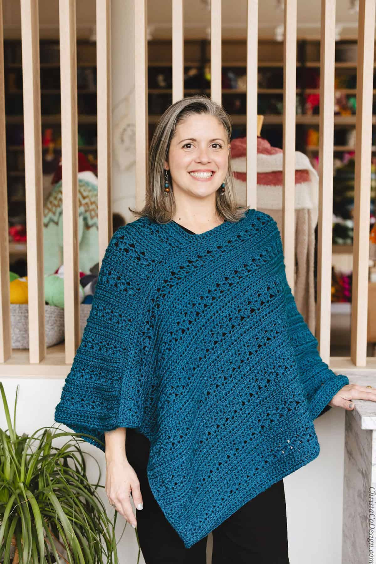 Smiling woman in crochet poncho.