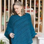 Woman looking down at crochet poncho in hand.