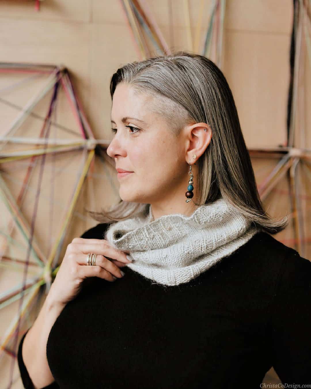 Woman turned to side holding grey cowl.