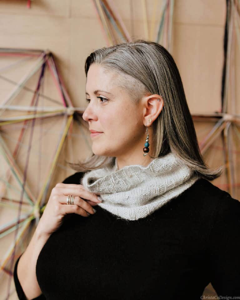 Woman turned to side holding grey cowl.