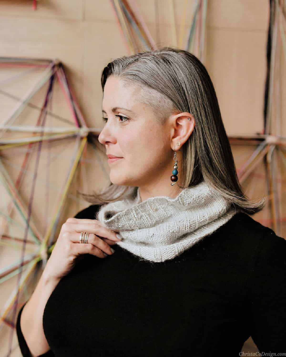 Woman turned to side holding grey cowl.
