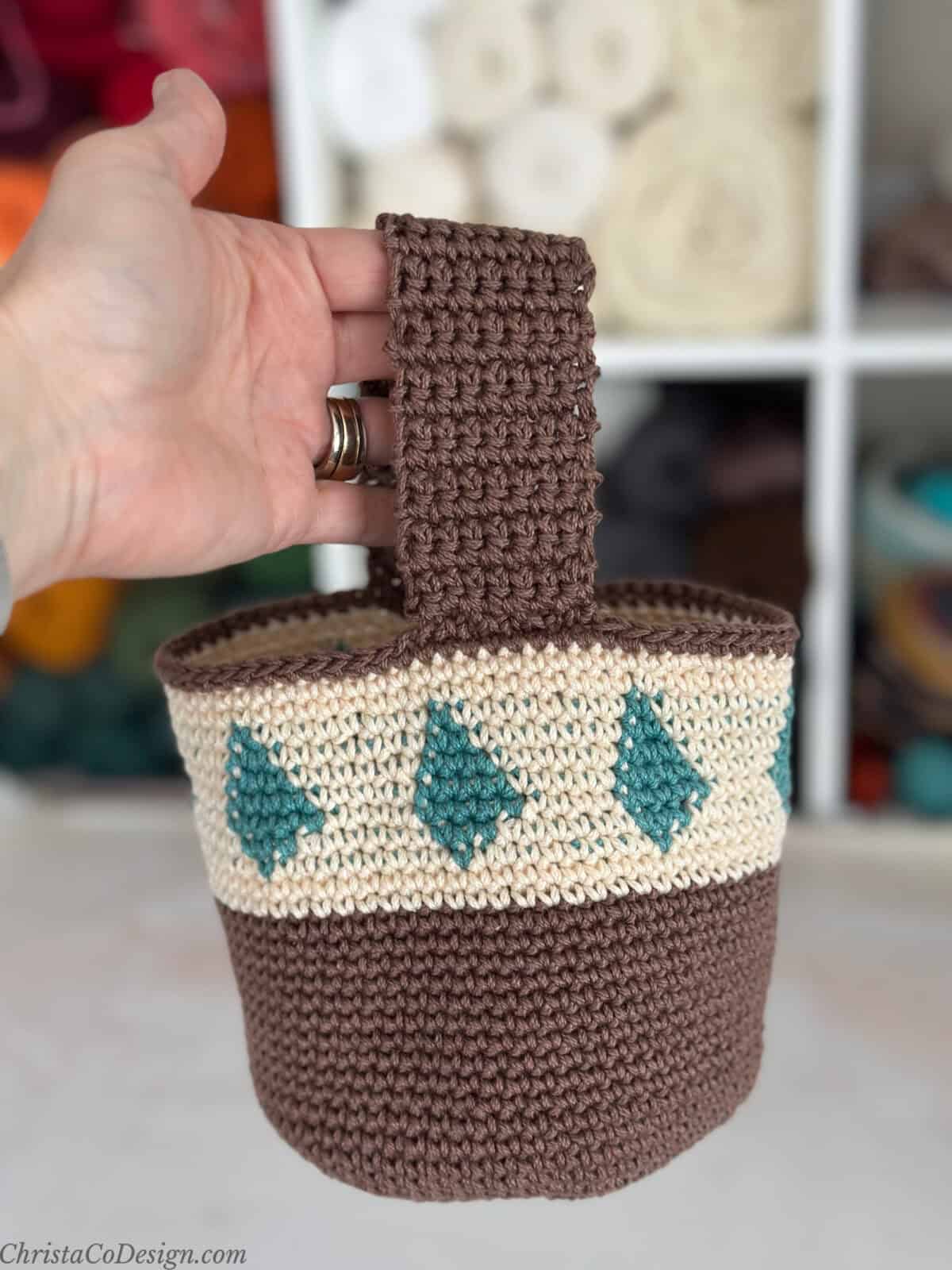 Hand holding up small crochet project bag.