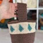 Hand holding up small crochet project bag.