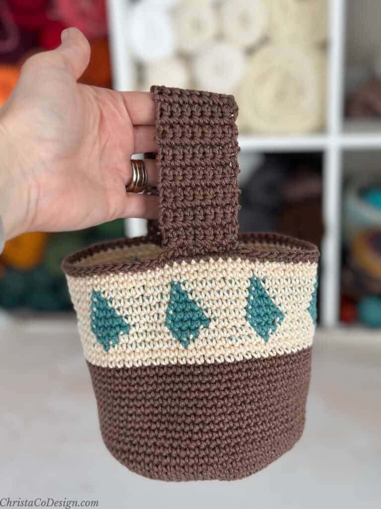 Hand holding up small crochet project bag.