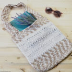 Flat lay of crochet bag with sunglasses and book.