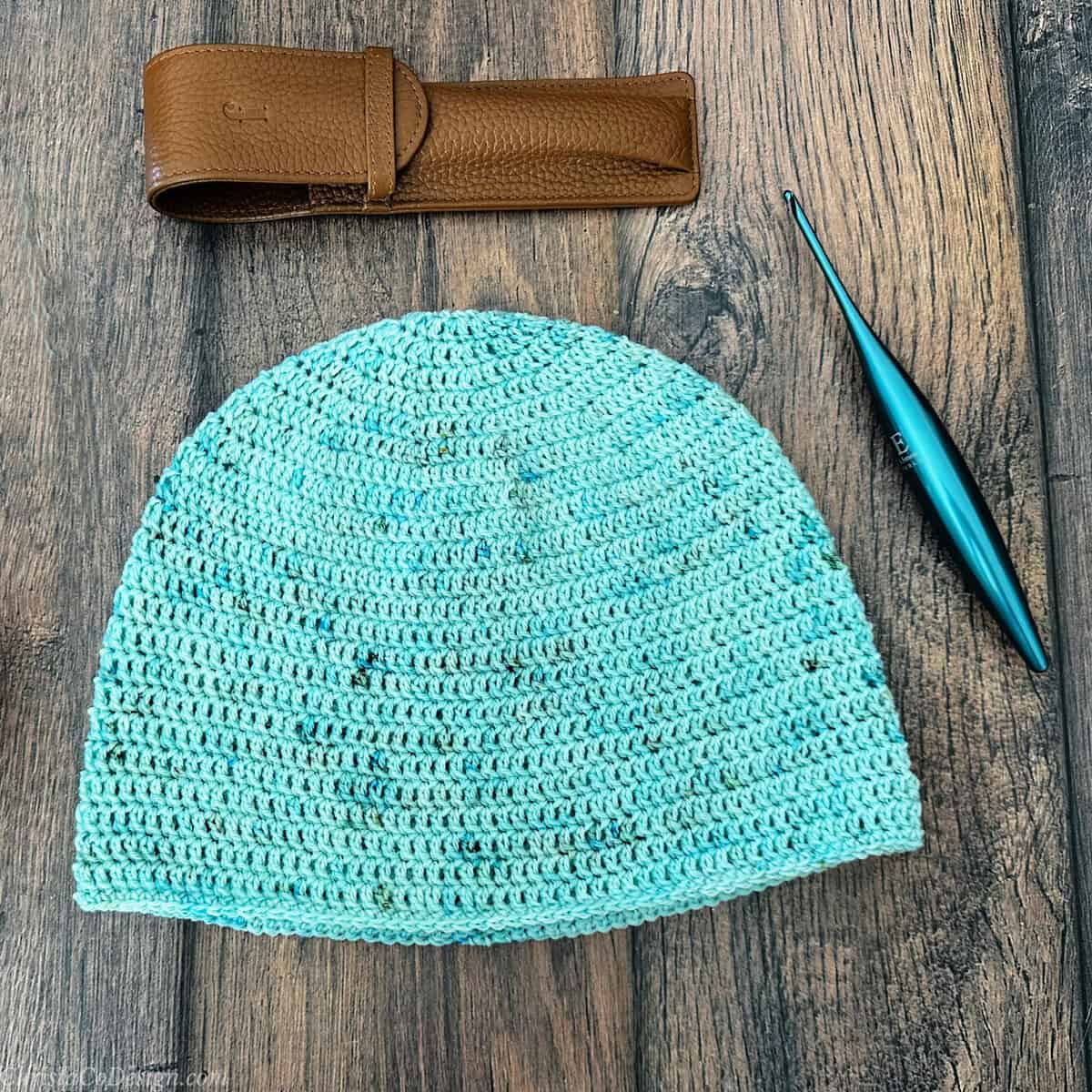 Flat lay of crochet hat with hook and case.