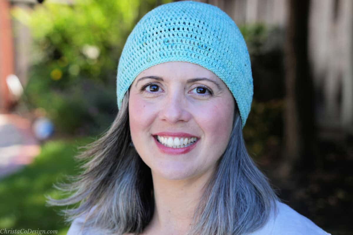 Woman smiling outside in blue beanie.