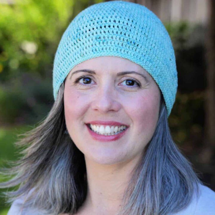 Woman smiling outside in blue beanie.