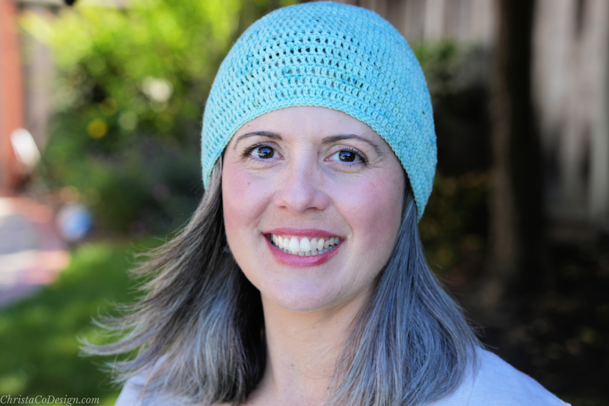 Woman smiling outside in blue beanie.