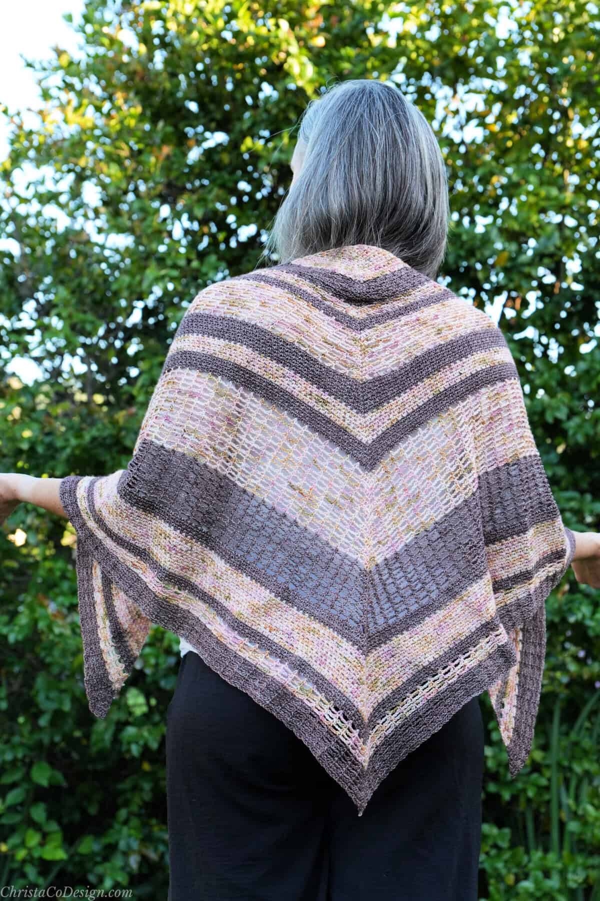 Woman with triangle shawl in pink and brown hand dyed yarn.