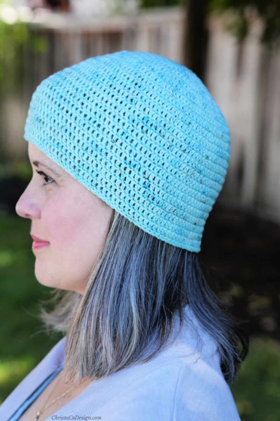 Woman in blue crochet hat turned to side.