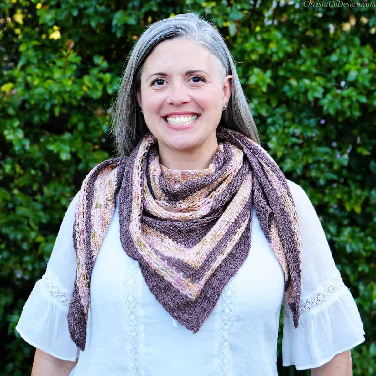 Woman smiling with triangle scarf draped over white shirt.