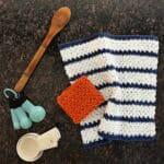 Crochet dish cloth in blue and white and an orange square with kitchen utensils.